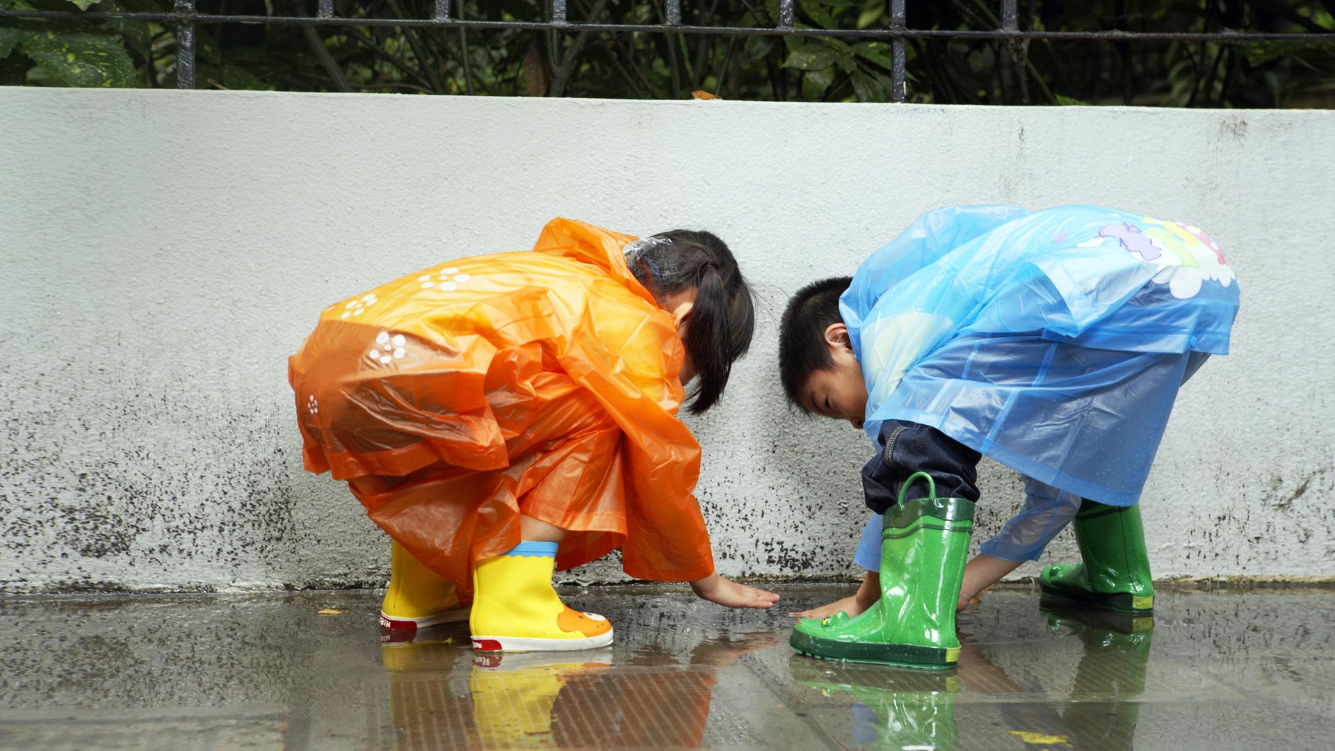 والپیپر منحصر به فرد از دوتا بچه زیر بارون با لباس های رنگی 
