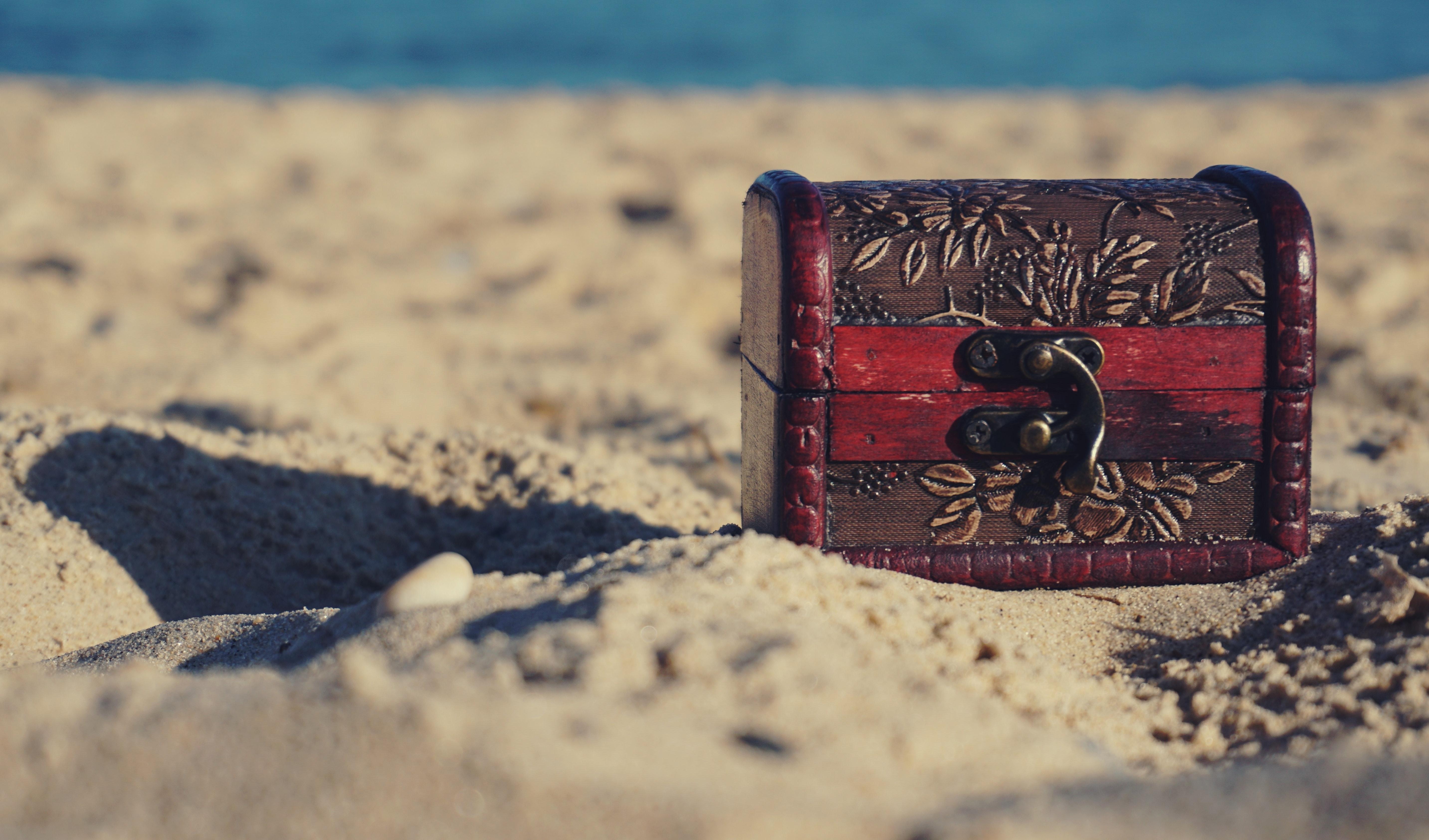 عکس صندوقچه فانتزی قرمز جذاب با طرح عجیب باستانی روی شنزار ساحل 