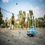 چاپ قاب موبایل و گوشی تصویر ماشین مینیاتوری قدیمی در ساحل با پس زمینه تار 