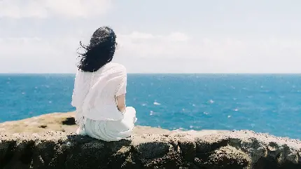 دختر تنها و غمگین نشسته کنار ساحل آرام دریا