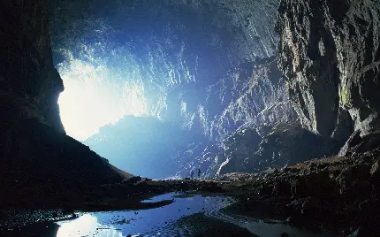 عکس غار تاریک بزرگ با روزنه های نور و گردشگران 