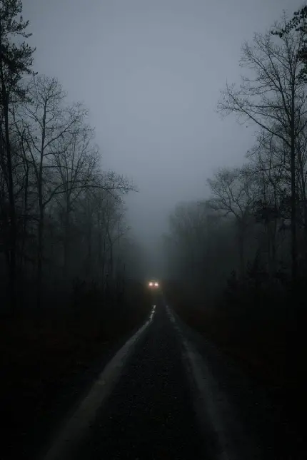 تصویر زمینه جاده خاکی و چراغ های روشن ماشین در تاریکی