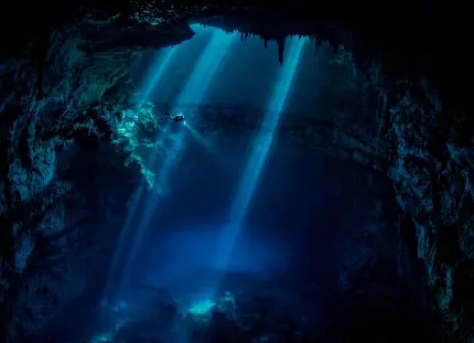 تصویر زمینه دهان غار تاریک و عجیب با سوسو نورهای آبی 