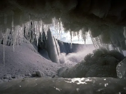 تصویر زمینه قندیل های یخی کریستالی دهانه غار تاریک و عجیب