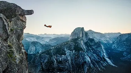 عکس کوهستان زیبا و پرواز انسان با لباس مخصوص حرفه ای