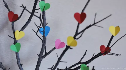 پس زمینه و والپیپر شاخه درخت با برگ های کاغذی قلبی رنگارنگ