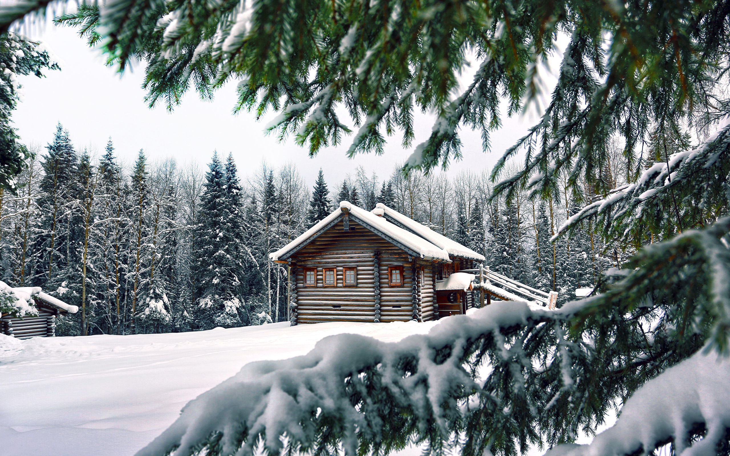 عکس فصل زمستان با برف های روی سقف کلبه های کوچک چوبی 
