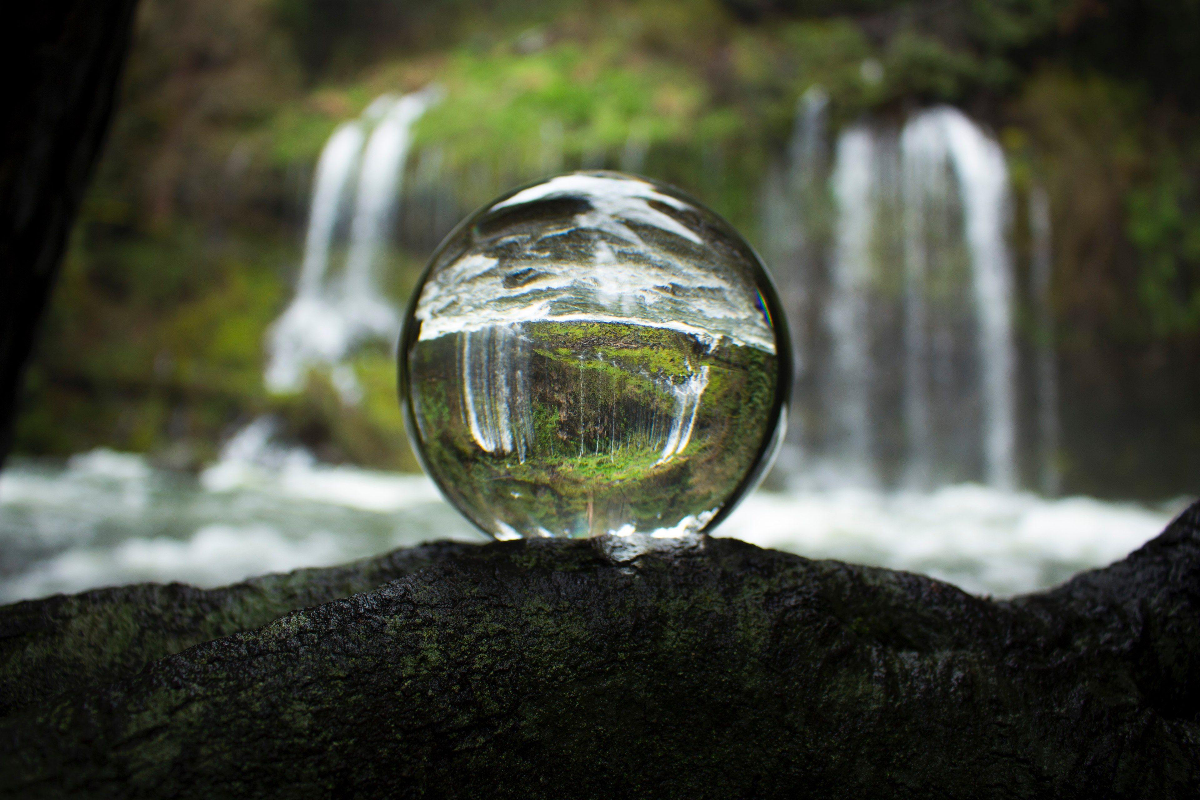 زیباترین عکس ادیت شده توپ کریستالی شفاف با پس زمینه آبشار طبیعی 
