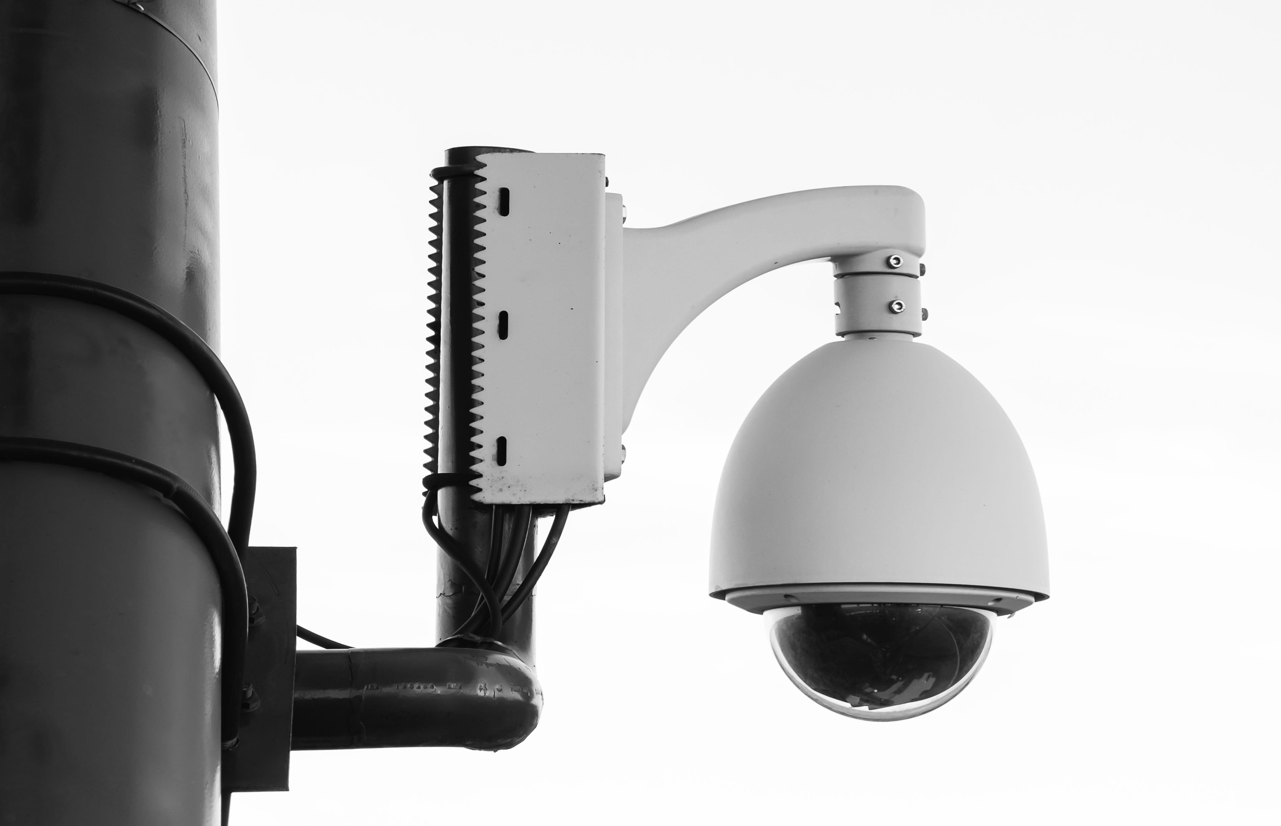 عکس استوک دوربین مدار بسته سفید متصل به تیر چراغ برق 