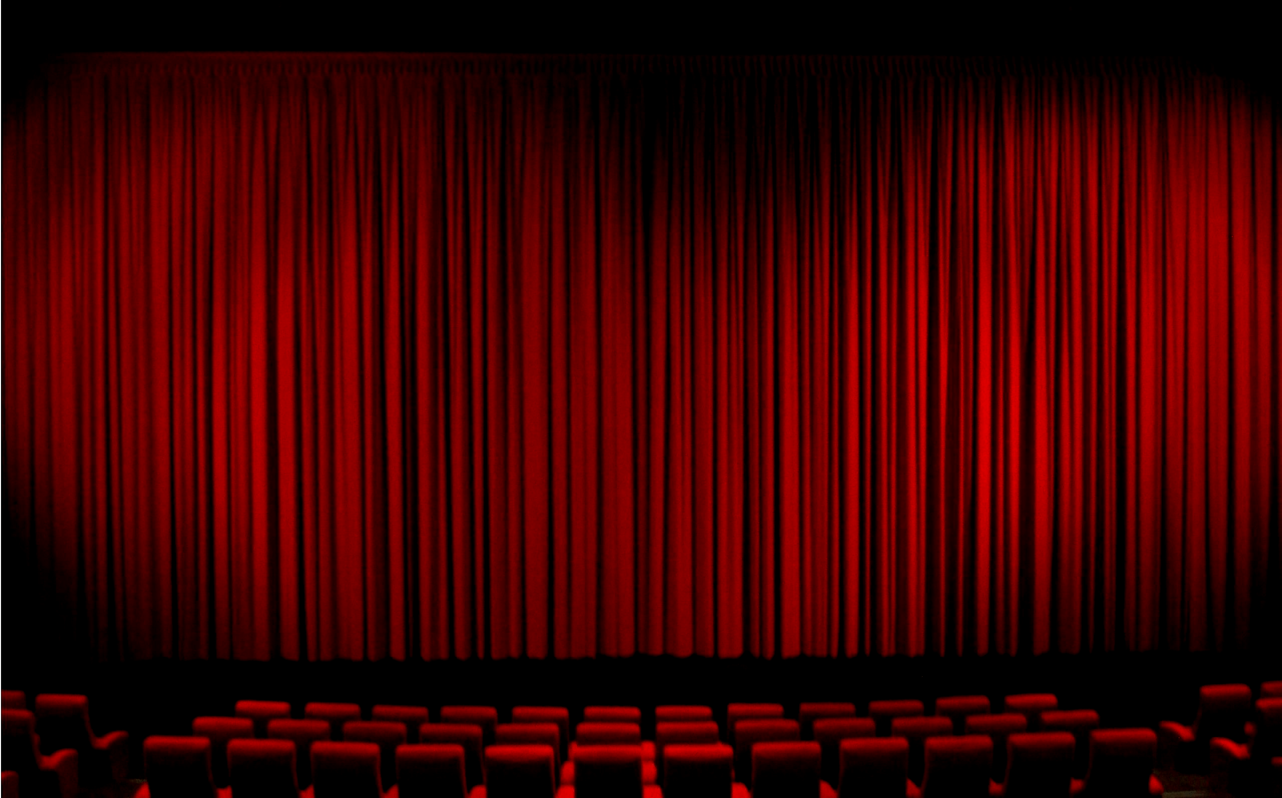 عکس پرده سینما در سالن چیده شده با صندلی های قرمز 