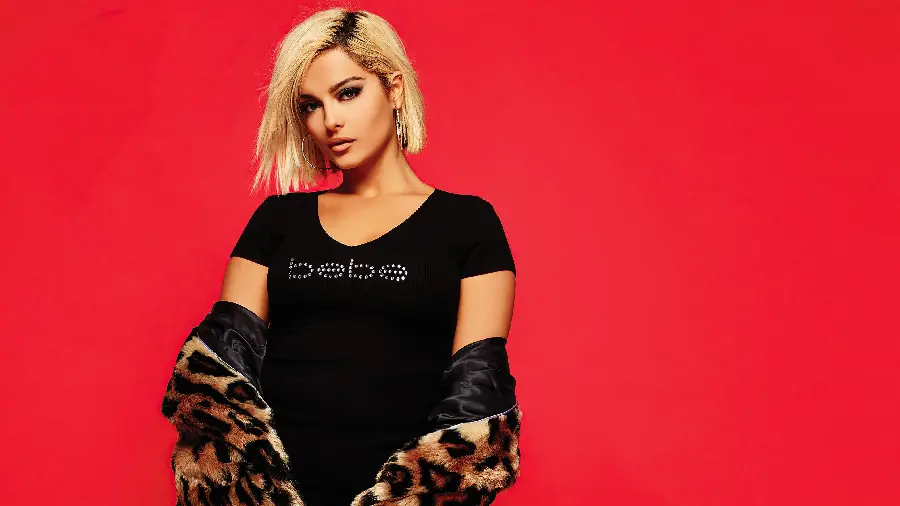 بی‌ بی رکسا Bebe Rexha با لباس مشکی و بکگراند قرمز 