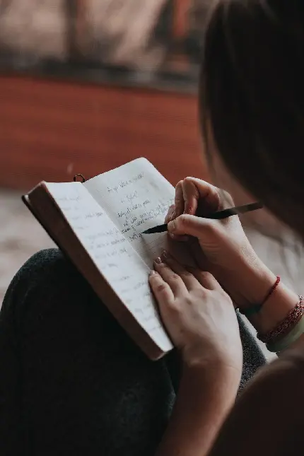 بک گراند دفتر نویسنده زن روی زانوهایش و نوشتن با خودکار