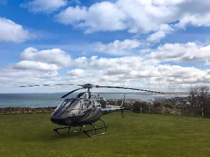 عکس استوک هلیکوپتر خصوصی با زمینه آسمان آبی پر از ابر 
