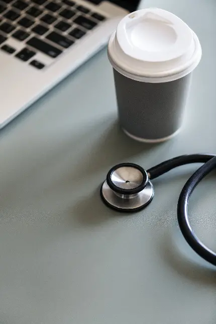 تصویر گوشی پزشکی در کنار لیوان قهوه با کیفیت بسیار بالا