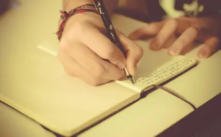 دانلود تصویر نویسنده زن با دستبند رنگارنگ و خودنویس