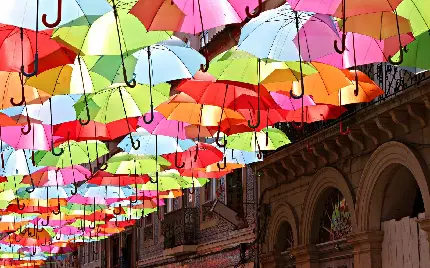 عکس سایه بان چتر های رنگارنگ در خیابانی با معماری محشر