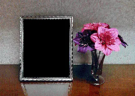 عکس قاب عکس خالی در کنار گلدان شیشه ای با گل های صورتی 