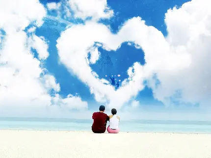 تصویر رمانتیک زوج عاشق در ساحل دریا رو به ابرهای قلبی شکل