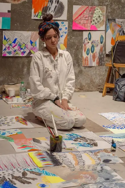 دختر نقاش خسته در میان تعداد زیادی نقاشی تماشایی