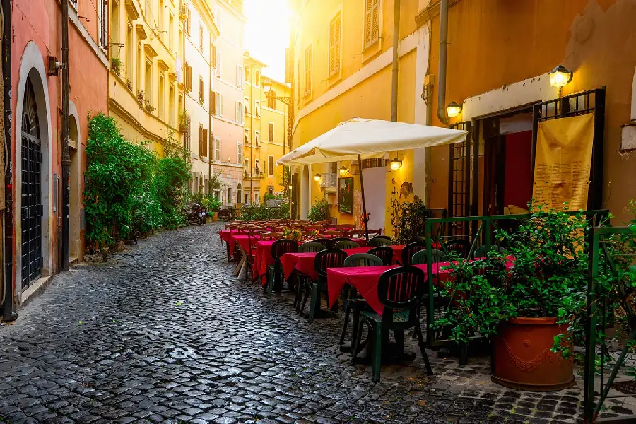 عکس کافه‌های ایتالیا و میز و صندلی‌های قرمز کنار سنگ فرش‌های خیابان تصویر با کیفیت بالا