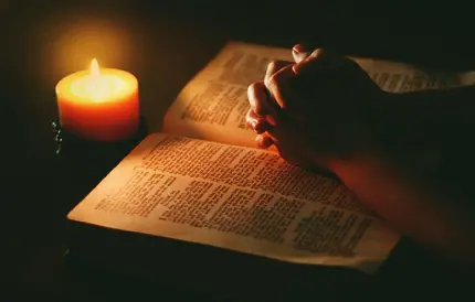دست های دعا کننده شمع و کتاب مقدس