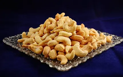 بادام هندی داخل بشقابی از جنس نقره روی پارچه مخملی سرمه ای