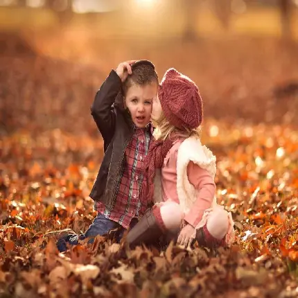 تصویر عاشقانه دختر و پسر بچه در پاییز میان برگ‌ها