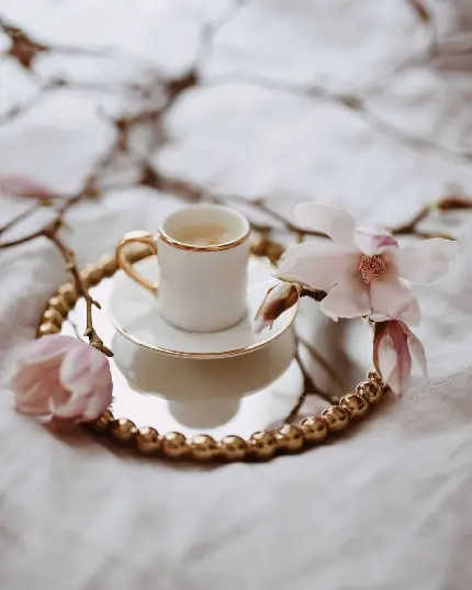 عکس فنجان قهوه کنار گل‌های بهاری با کیفیت بالا
