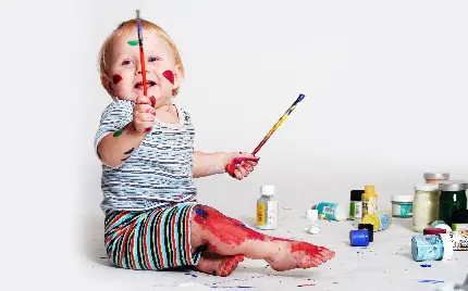 دختر بچه نقاش در حال کشیدن نقاشی با رنگ‌های واقعی