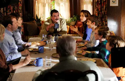 عکس خانواده خوشحال در حال صحبت در کنار میز شام